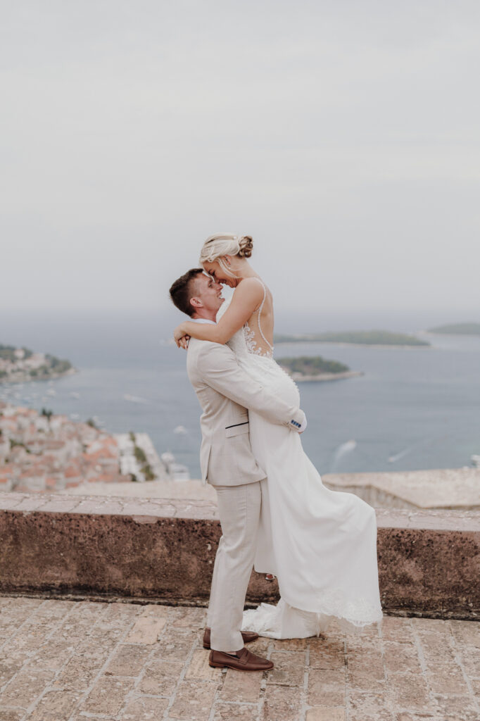 Groom picking up bride on Spanish fortress Hvar, Croatia