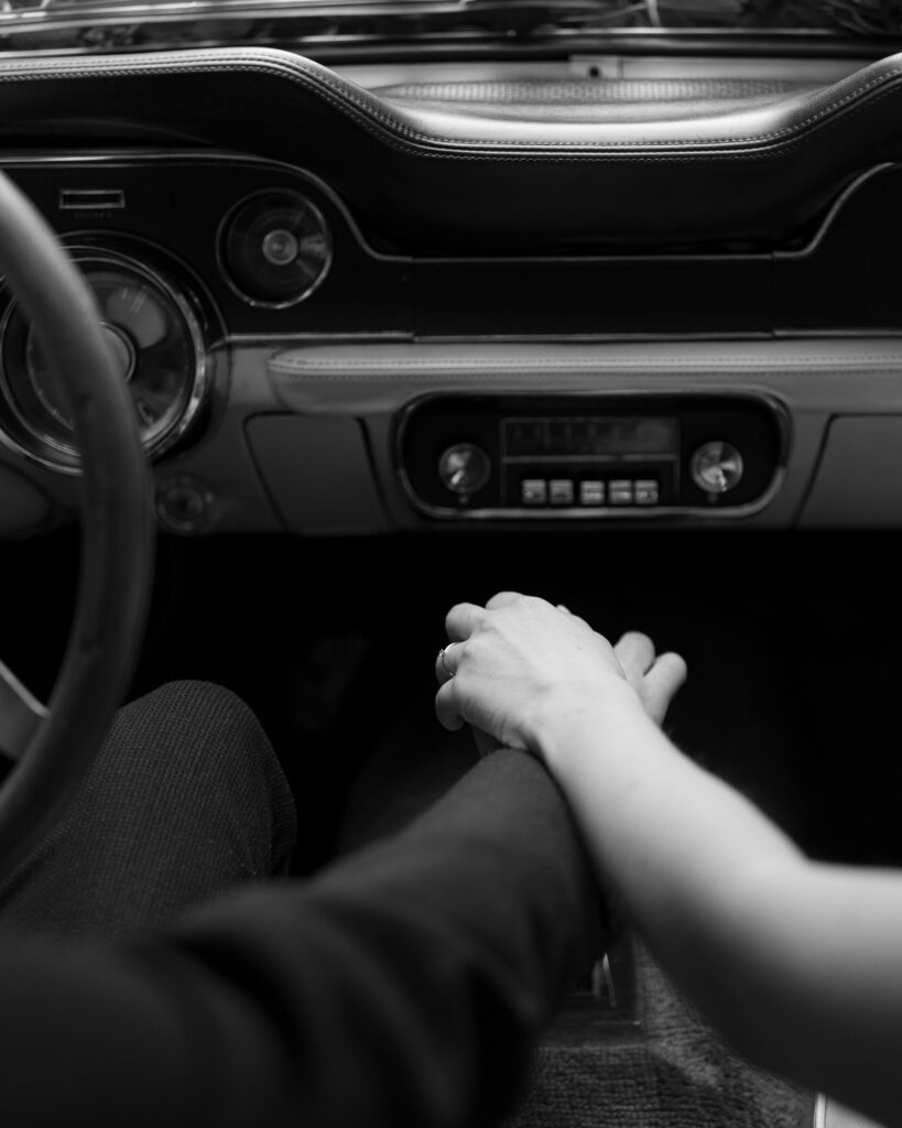 Couple holding hands in an old Mustang