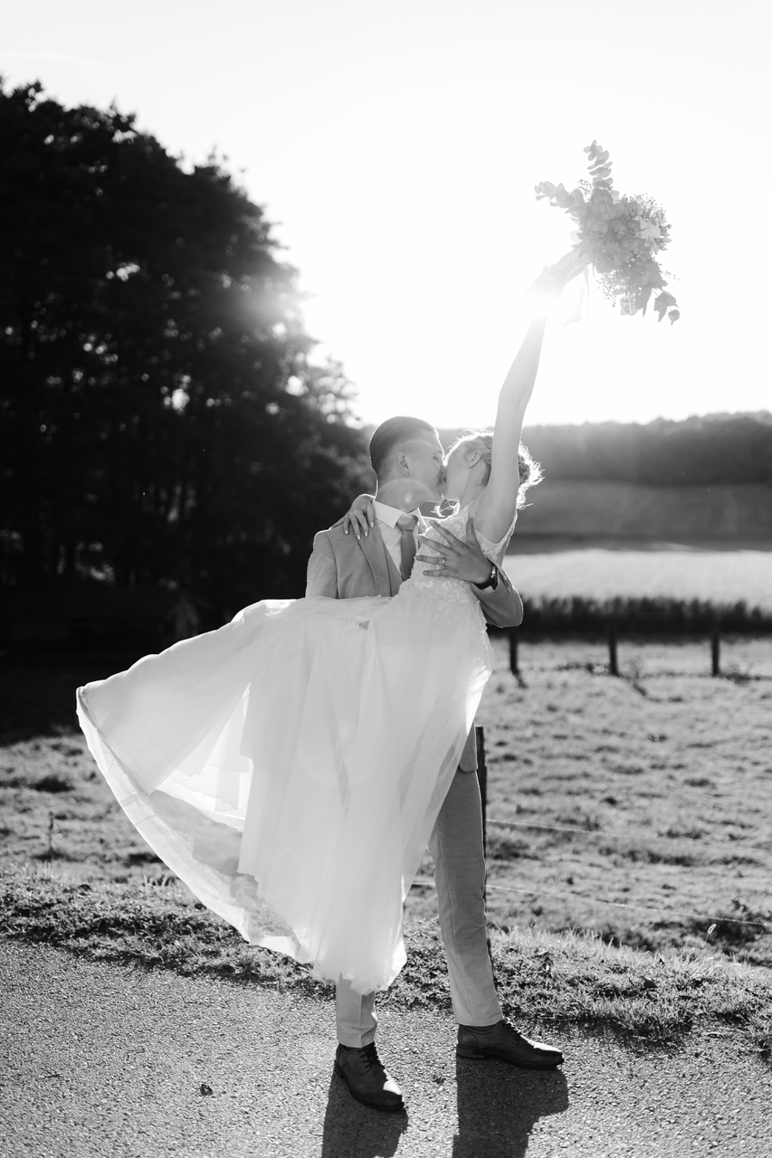 Groom holding and kissing his bride at Seoski turizam Rakić